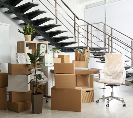 Cardboard boxes and furniture near stairs in office. Moving day